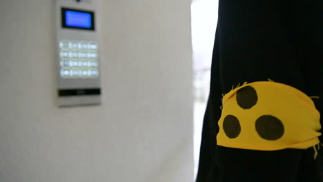 rear view of a blind man keying in numbers into the security system at a building entrance