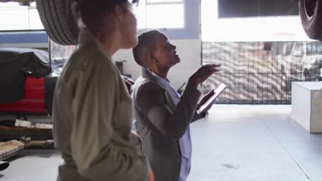 Video-of-two-diverse-female-car-mechanic-and-business-owner-with-tablet-checking-car