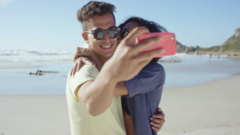 hermosa pareja de raza mixta tomando selfies en la playa