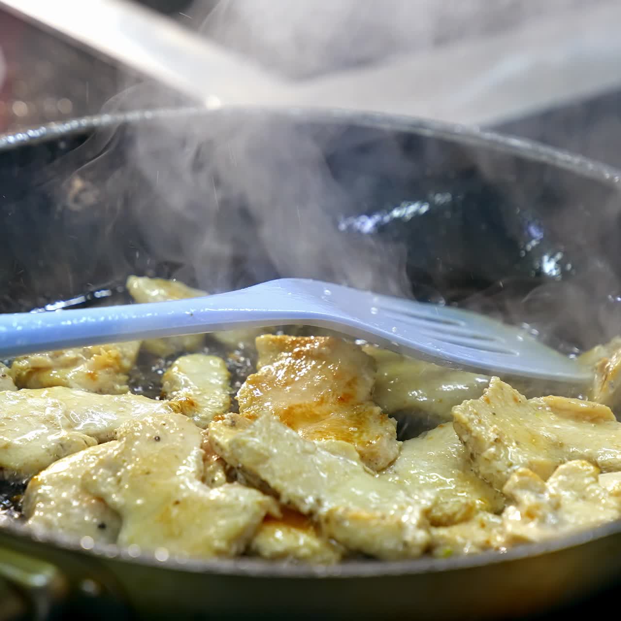 Pieces of meat in a frying pan. Cooking chicken meat in a hot frying pan. Preparation of tasty dish. Close-up