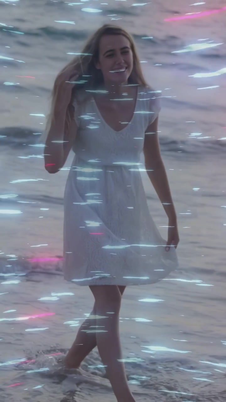 Vídeo vertical: Mulher entrando no quadro, arrumando o cabelo, caminhando na areia com detalhes neon para moda.