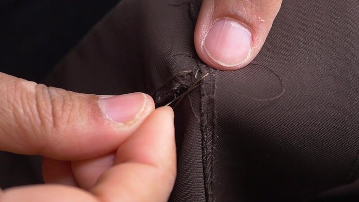 Close-up of Hands Hand-Sewing Brown Fabric