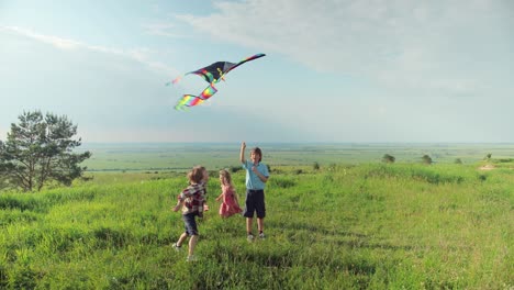 full length view of little children having fun in the park while flying a kite on a sunny day