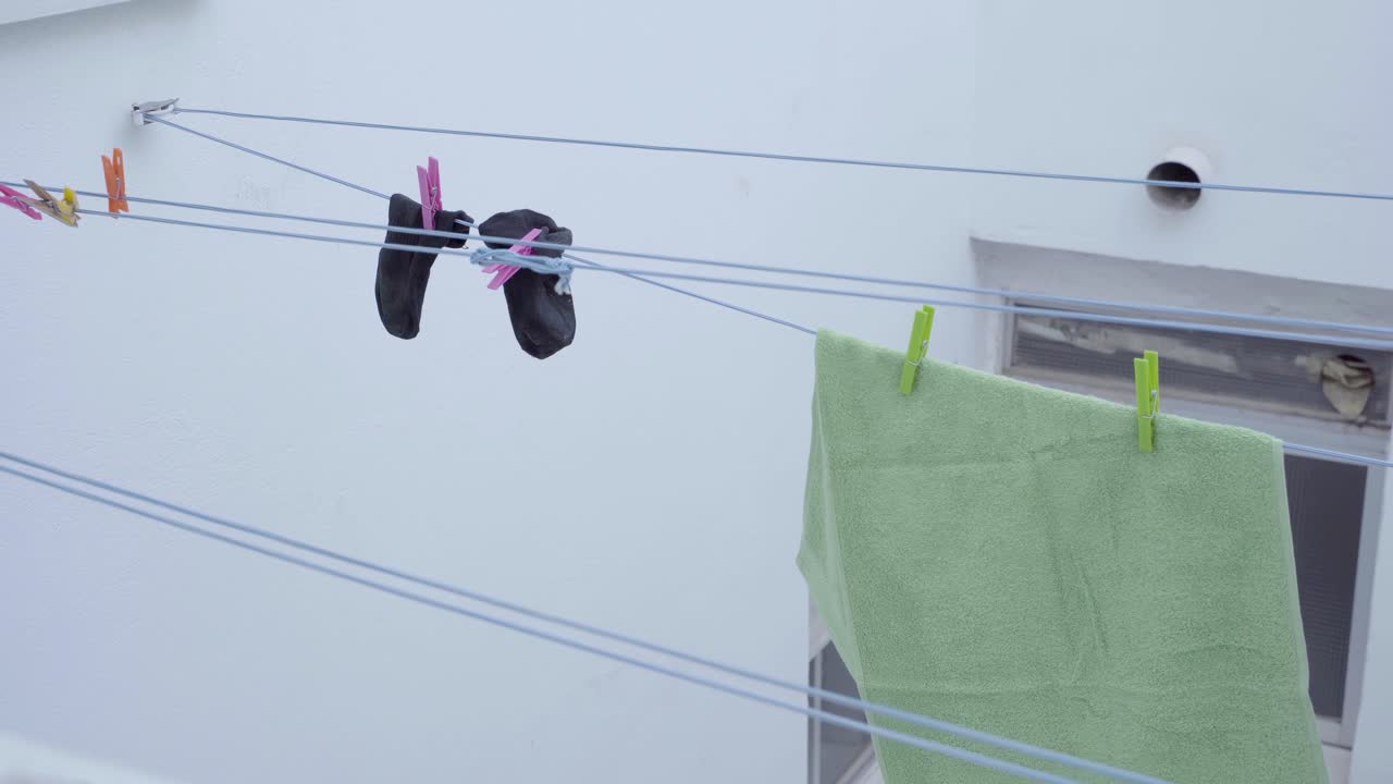 Clothes hanging on outdoor drying rack on overcast day, slow panning movement