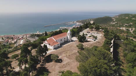 aerial forward view of ancient walls with church and sea in background. sesimbra, portugal