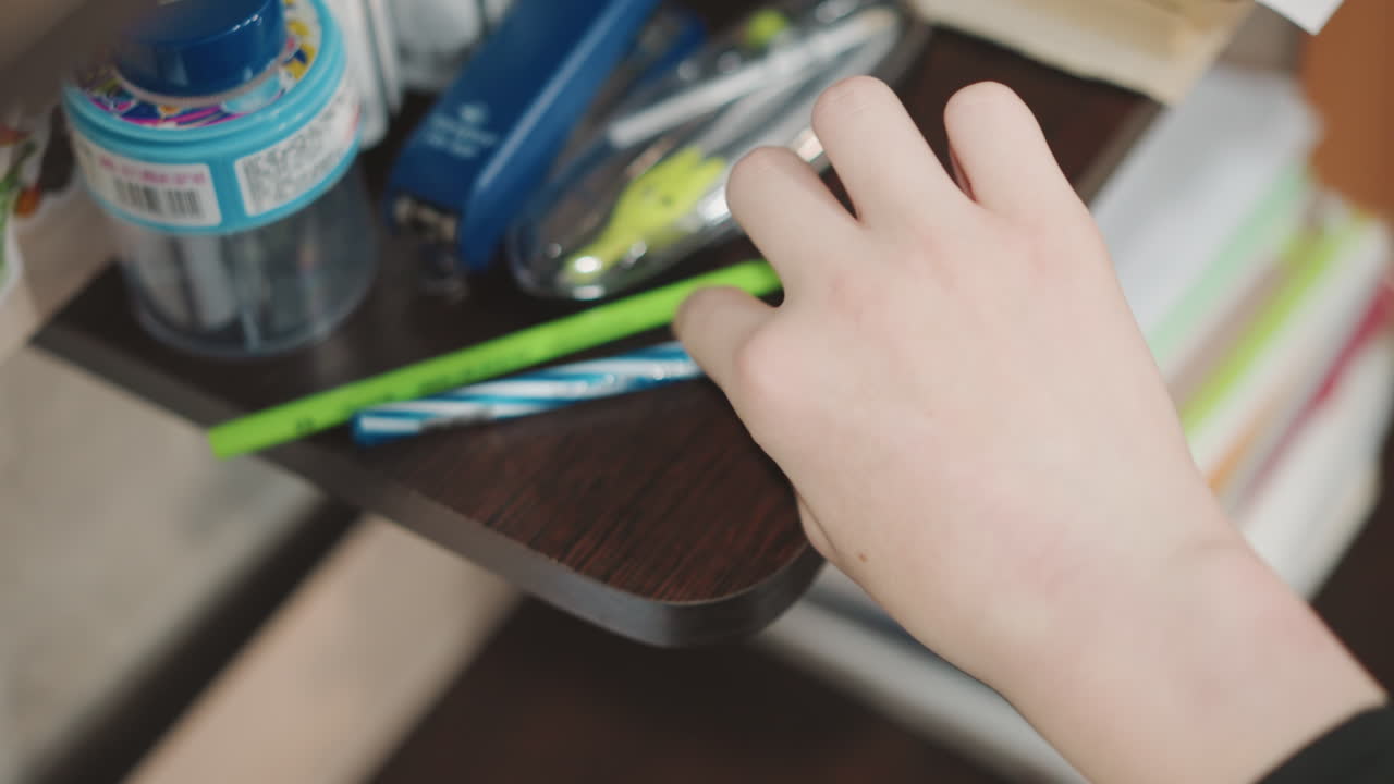 Child chooses bright pencil. Grandson picks vibrant writing instrument. Young boy selects colorful pencil for drawing activity. Child carefully chooses luminous pencil before beginning to write