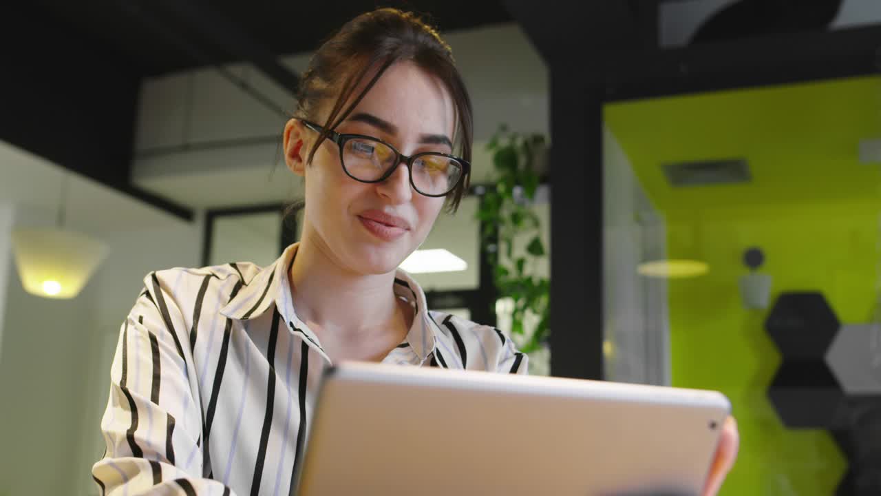 mujer con gafas usando tableta en la oficina de inicio