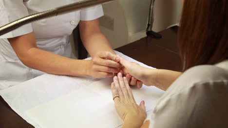 Nail-technician-examining-customers-hands