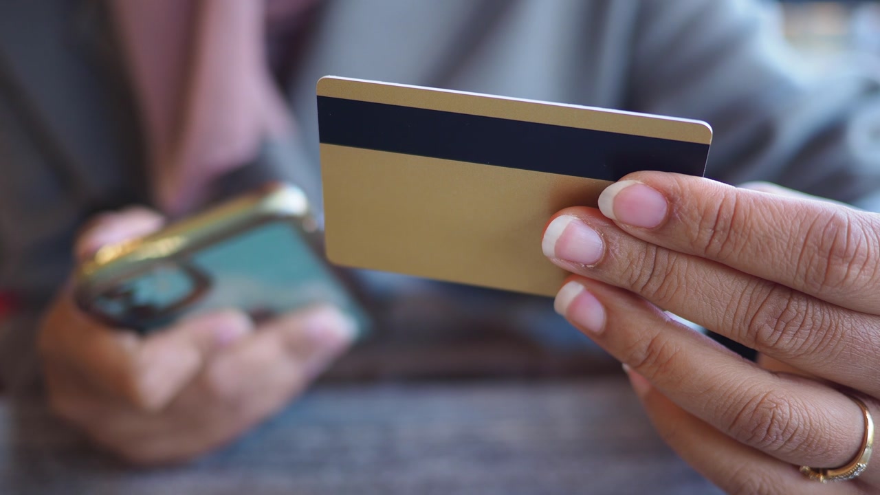 Close-Up of Hand Holding Credit Card and Smartphone for Online Transaction