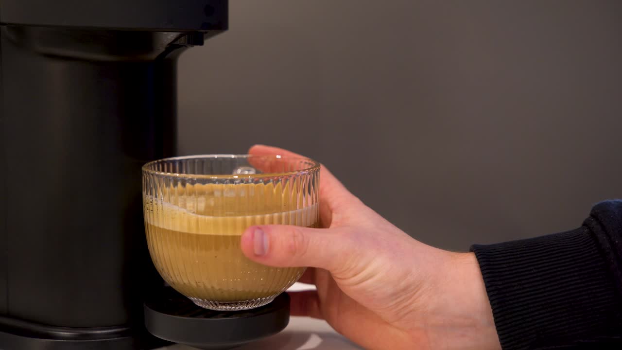 mano masculina recogiendo un café con leche de una máquina de espresso