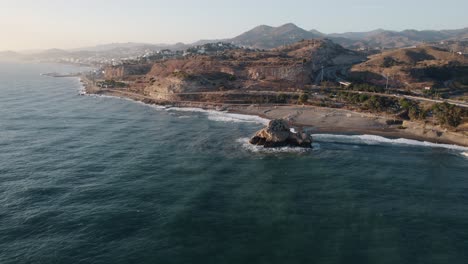 cinematic aerial zoom in on the famous raven rock of el peñón del cuervo that splits the bay into two beaches on the coast of the alboran sea in malaga spain