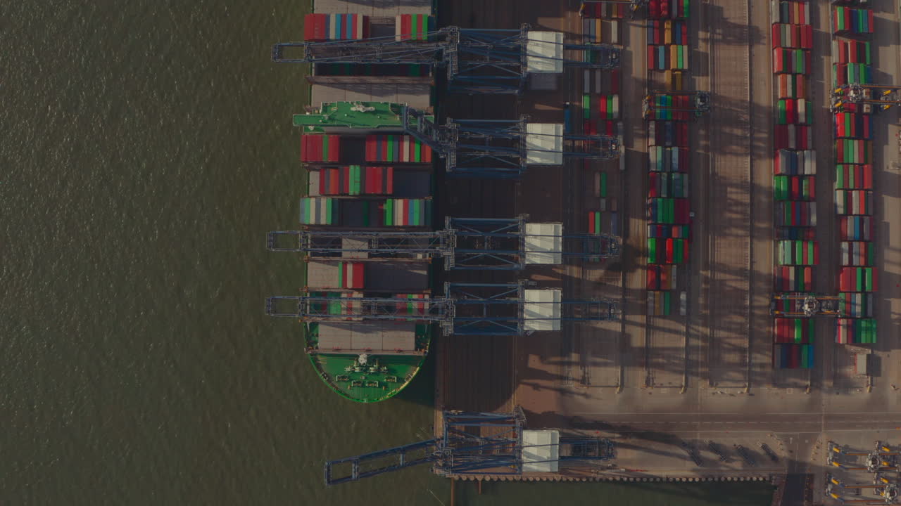 Top down drone shot over cranes loading large container ship at Port of Felixstowe