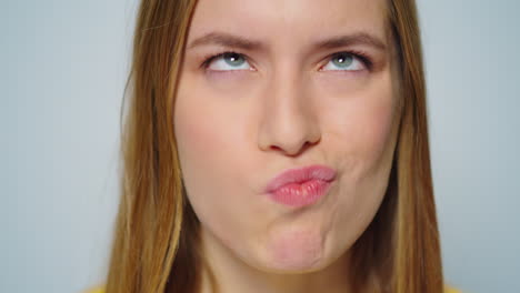 Closeup-cheerful-woman-making-funny-faces-on-grey-background-in-studio.