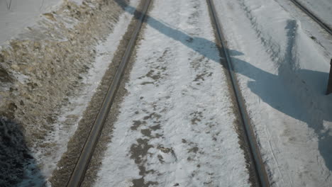 train rails streak past snowy ground as fast carriage moves along winter route, ground level view with parallel tracks, frost, long shadow, strong motion sense, cold travel mood in steady glide