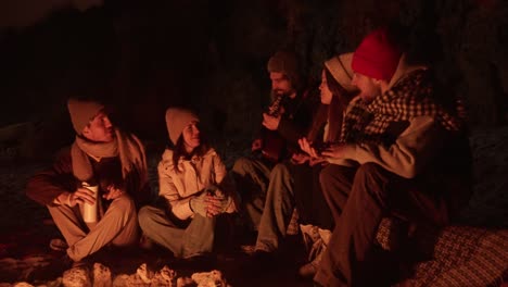 friends singing around a campfire at night