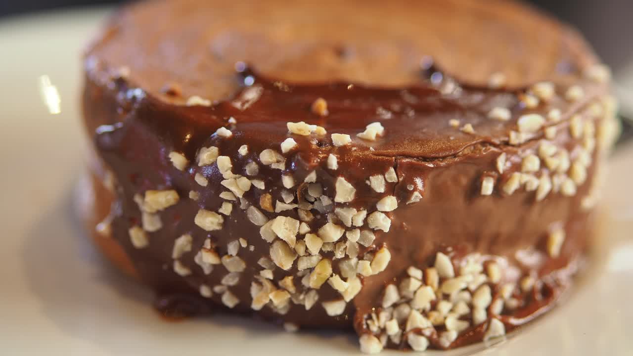 Close-up of a chocolate cake with chocolate icing and chopped nuts