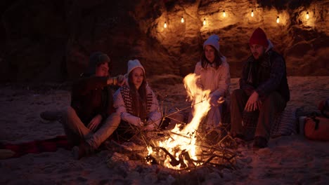 amigos disfrutando de una fogata en la playa por la noche