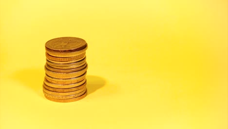 la mano apilando diferentes monedas en un fondo colorido