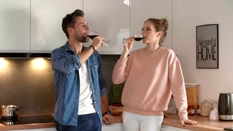 Pareja-Feliz-Bebiendo-Vino-Tinto-En-La-Cocina