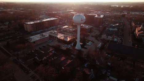 orbiting-around-libertyville,-illinois-water-tower-tank-at-the-sunset