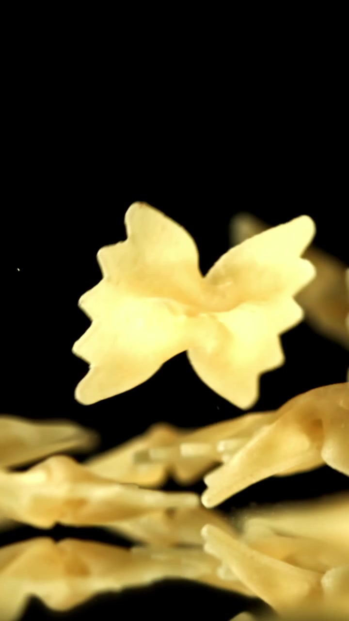 Movimento rallentato di pasta farfalle che cade su sfondo nero