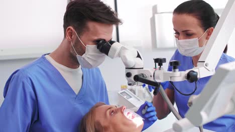 male dentist looking through dental microscope