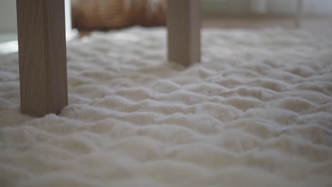 white faux fur rug with wooden table legs