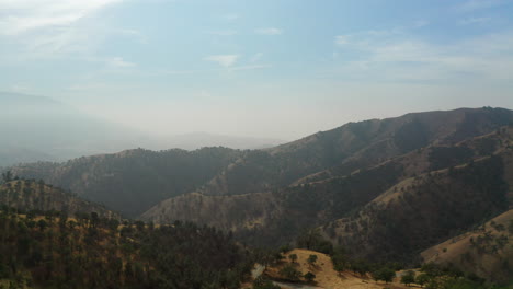 Smoky-haze-from-wildfires-pollute-the-sky-above-the-Red-Mountain-range-in-Southern-California---descending-aerial-view