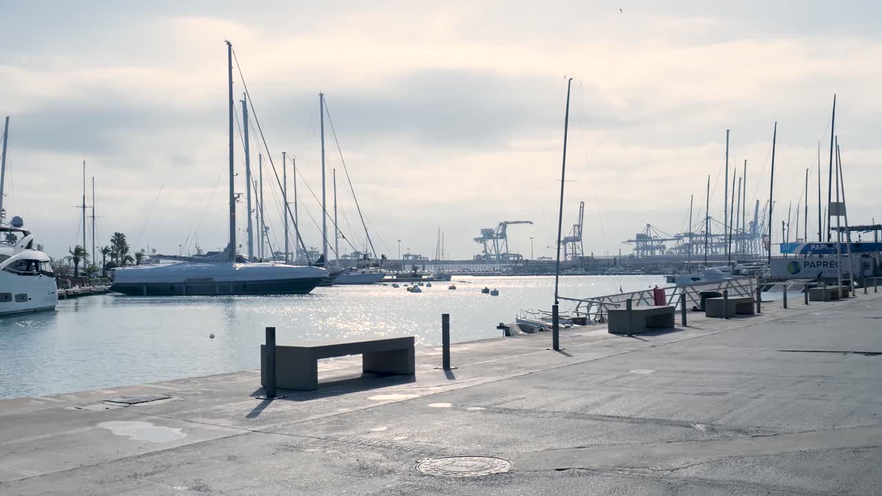 Marina with yachts and industrial port background