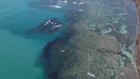 aerial flyover of shallow fringing reef and clear turquoise waters along tropical island coastline at catanduanes, philippines
