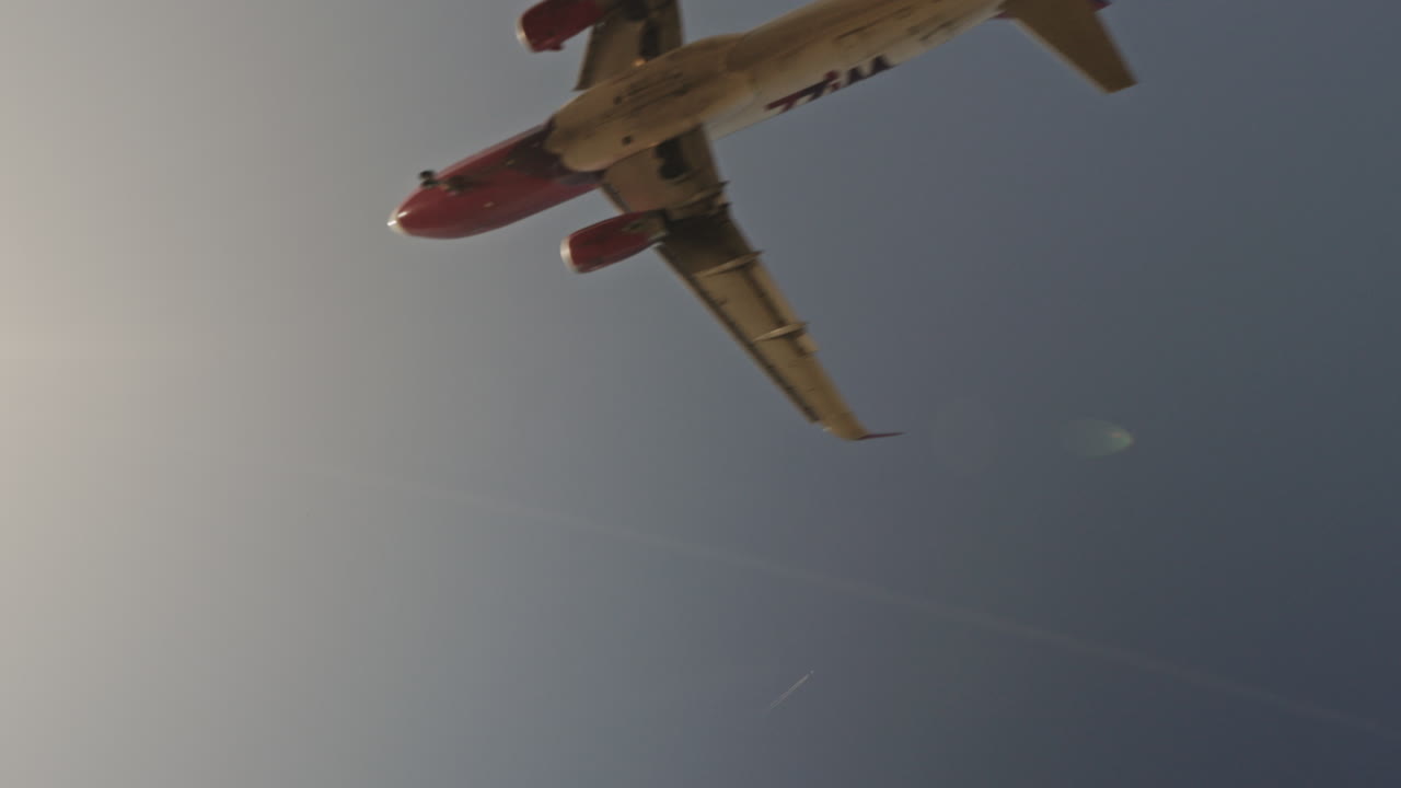 공항에 착륙하기 위해 석양 아래에서 매우 느린 속도로 머리 위를 날아가는 비행기