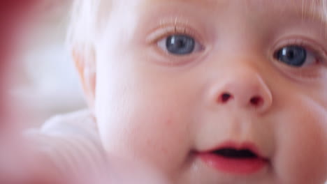 white toddler boy making face, reaching to camera, close up