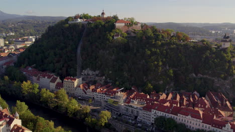 Aerial-rising-view-above-Uhrturm-clock-tower-on-Graz's-Schloßberg-dolomite-woodland-hilltop-in-Austria
