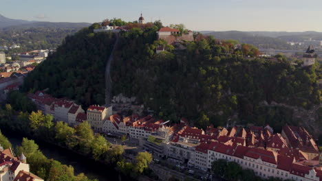 vista aérea ascendente sobre la torre del reloj uhrturm en la cima de la colina del bosque de dolomita schloßberg de graz en austria