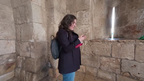 woman using phone in an ancient stone tower