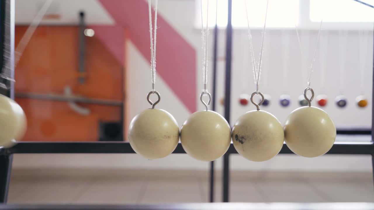 Hand holding a pendulum ball. Newton's cradle