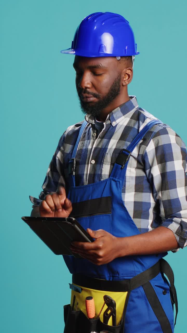 Vertical video: Confident mechanic using tablet for calculations