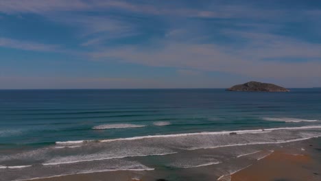 Remote-rocky-island-in-the-ocean-with-rolling-waves-in-different-shades-of-ocean-blue-water