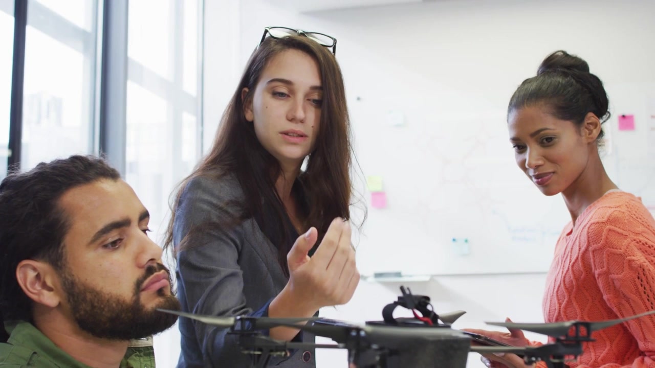 Team checking drone while lead pointing, social icons appearing, obscuring view for prototype demo