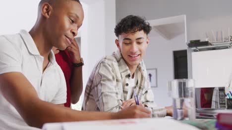 Three-happy-diverse-male-teenage-friends-writing-and-talking-at-home,-slow-motion