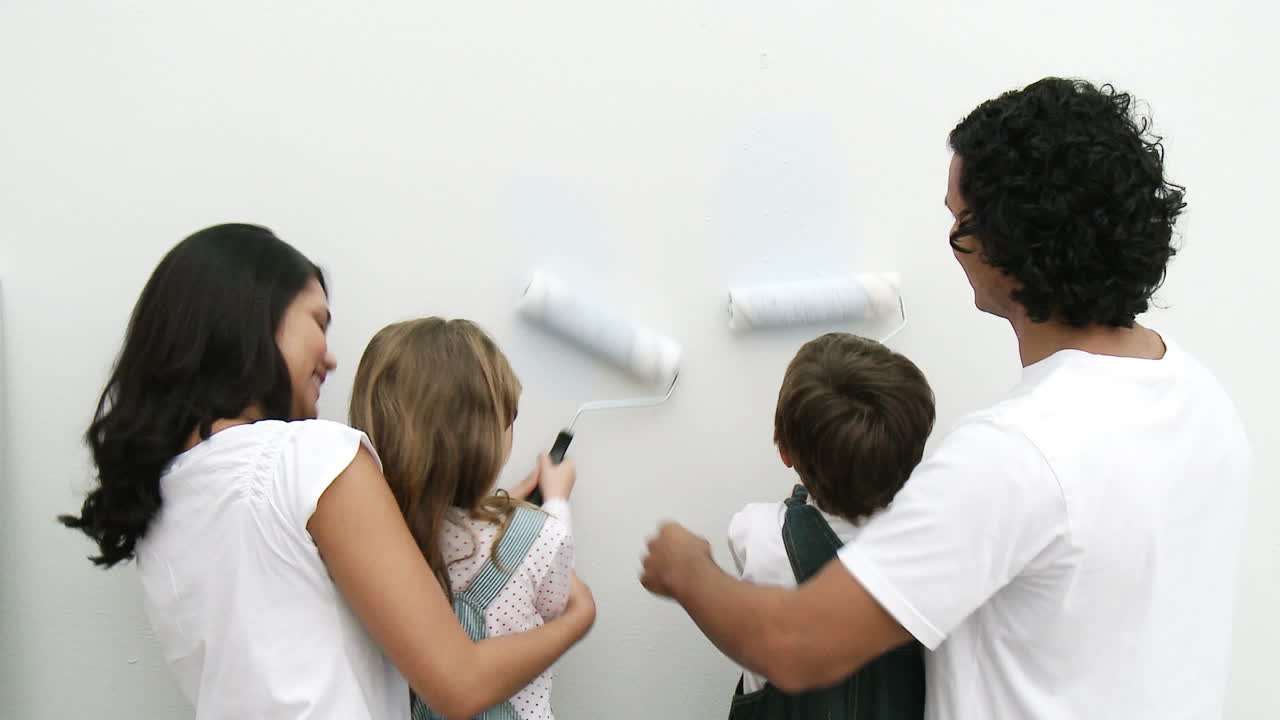 Family painting a wall at home with brushes