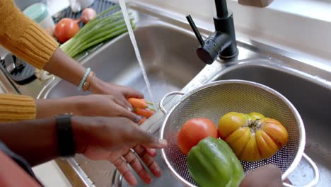 Hands-of-african-american-couple-rinsing-vegetables-in-kitchen,-slow-motion