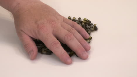 Capsules-filled-with-cannabis-infused-oil-on-white-table-moved-by-hand