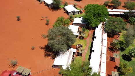 Backwards-drone-shot-of-a-lodge-in-Namibia-with-small-houses-and-a-pool