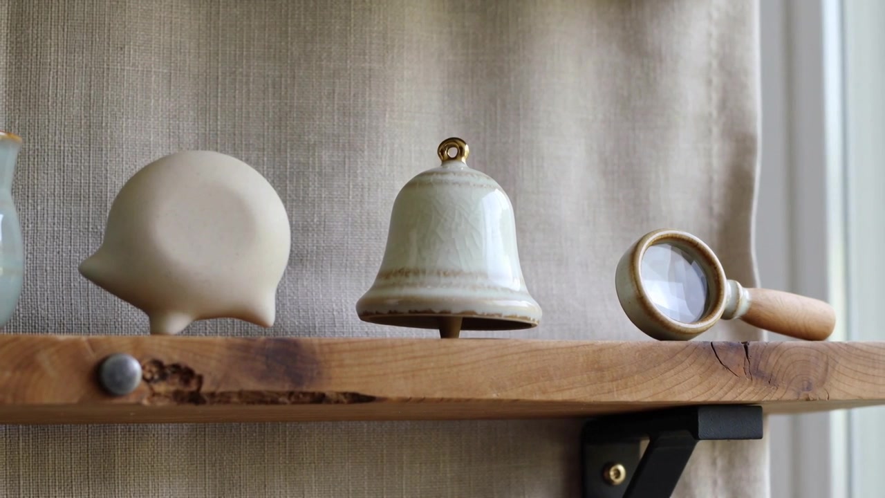 Swaying small tabletop trio on home wall shelf, bell tilting, lens rotating from slight vibration