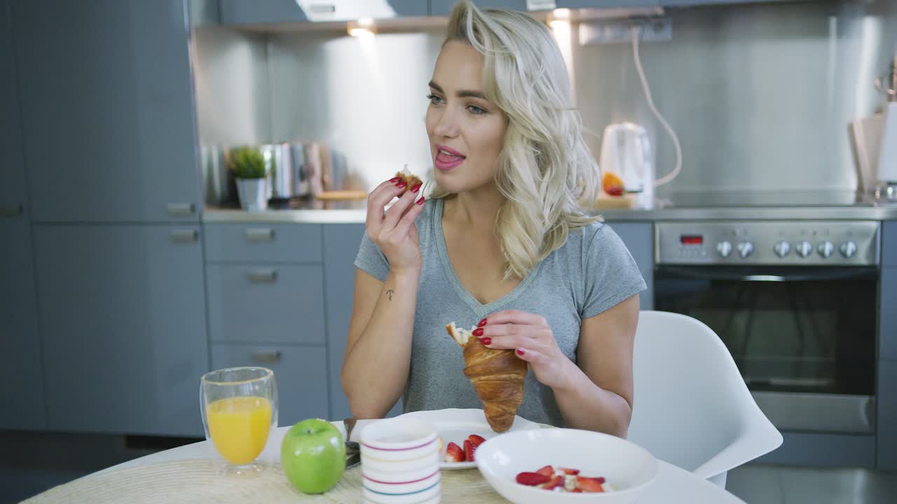 mujer comiendo croissant para el desayuno