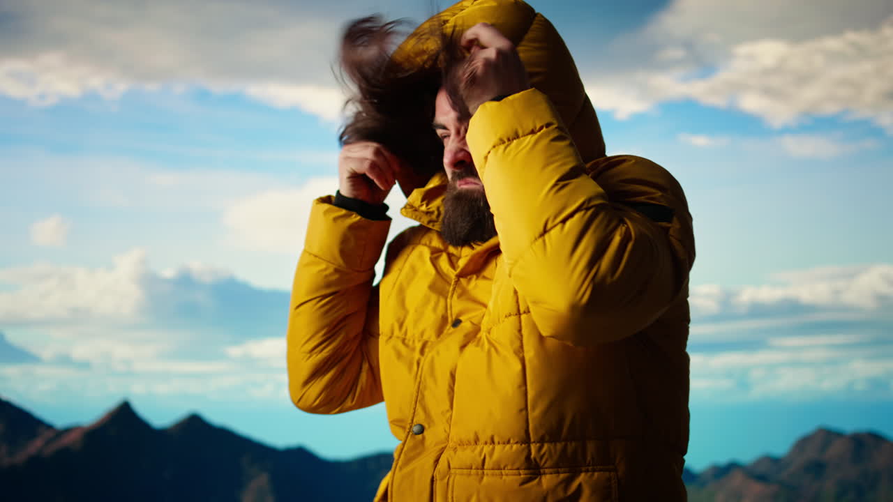 Young traveler hiker dealing with cold weather and wind at the mountain top