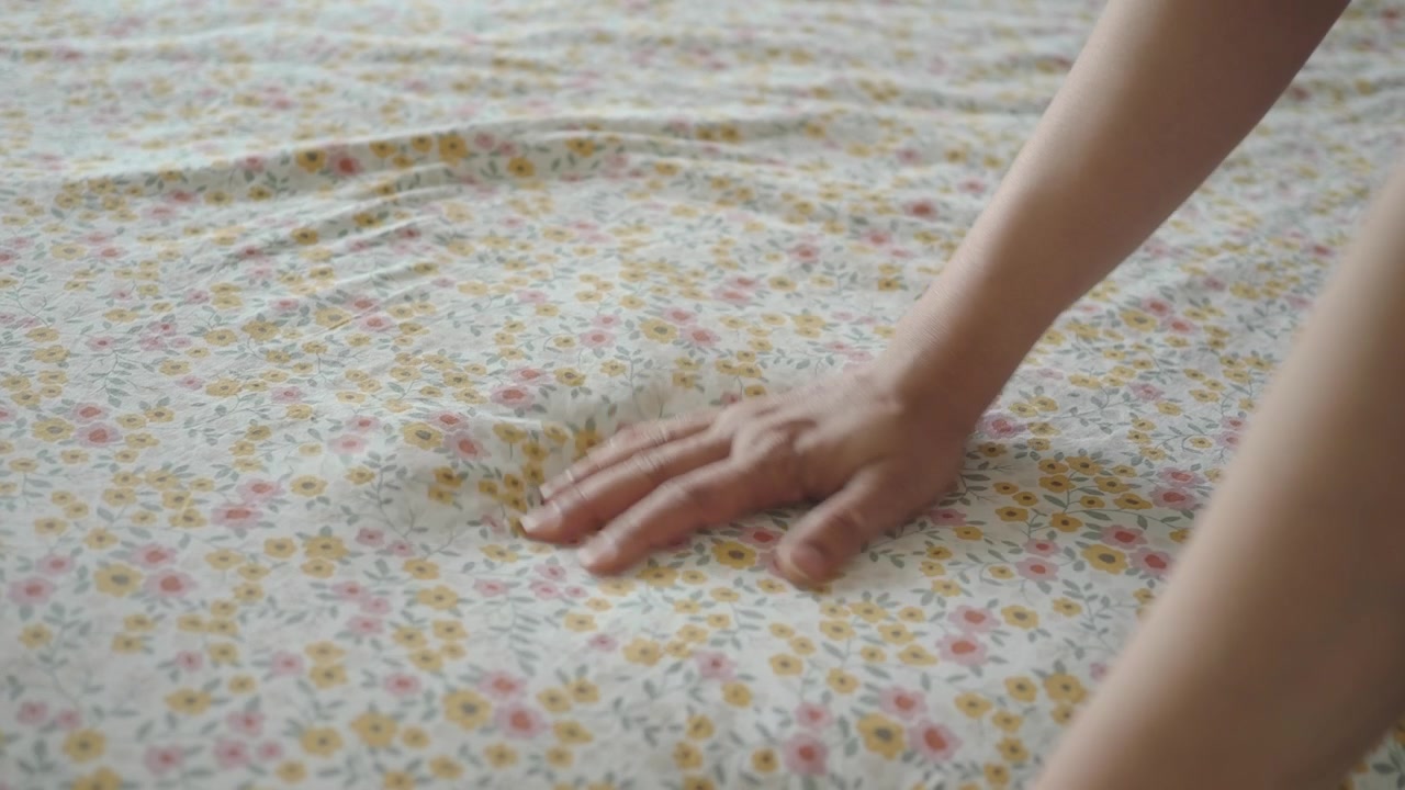 Mano che testa la morbidezza di un lenzuolo floreale