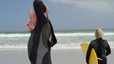 viejo hombre caucásico mayor con traje de neopreno en la playa 4k