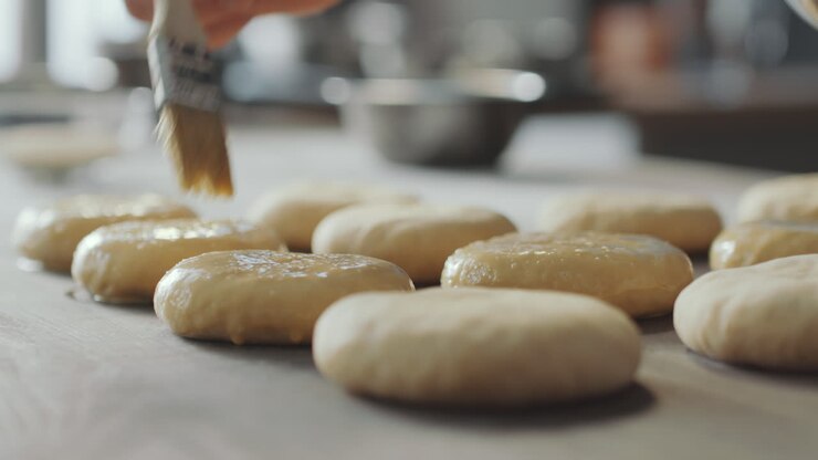 Brushing Egg Wash on Top of Burger Buns before Baking